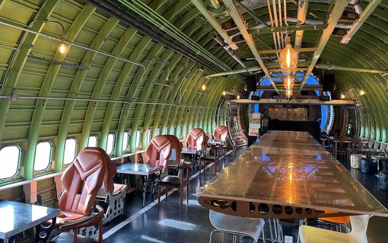 Intérieur du Boeing 747 Coffee Shop, transformé en café unique avec des sièges en cuir, des tables modernes et la structure originale de l'avion visible