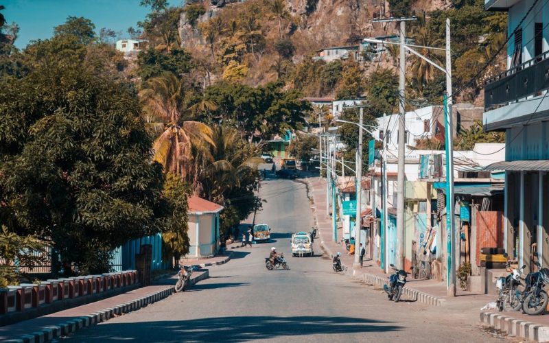 Rue paisible de Dili au Timor oriental, avec des maisons colorées, des motos et des collines rocheuses en arrière-plan