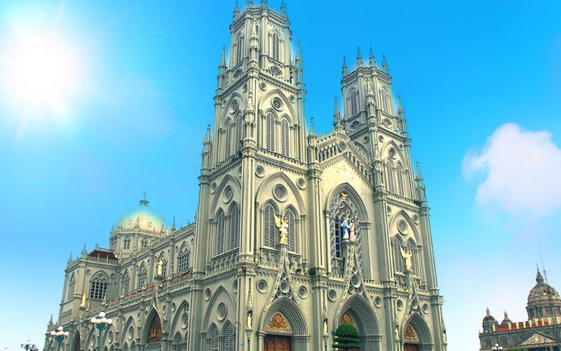Cathédrale majestueuse de style néogothique à Nam Dinh, avec ses deux hautes tours, ses vitraux colorés et ses statues religieuses, sous un ciel bleu éclatant
