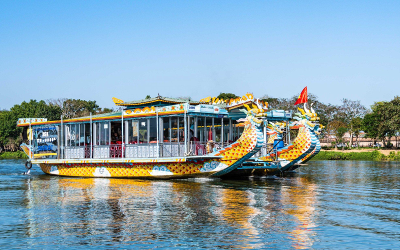 Bateau-dragon traditionnel naviguant sur la rivière des Parfums à Hué, Vietnam, par une journée ensoleillée, emblème culturel et touristique de la région.