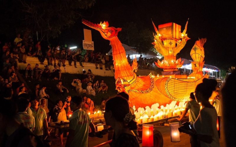 Grand bateau-lanterne en forme de naga illuminé lors du Boun Lai Heua Fai à Luang Prabang, entouré de spectateurs et de participants en fête