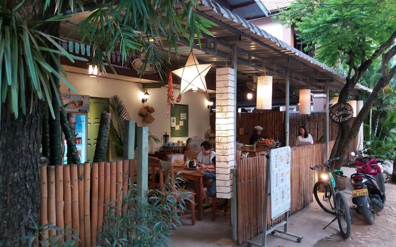 Terrasse d’un petit restaurant local à Luang Prabang, avec une décoration en bambou, des lanternes suspendues et une ambiance chaleureuse en plein air