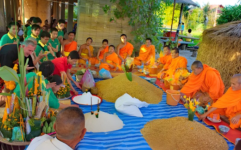 Cérémonie du Boun Khun Khao au Laos avec des moines bouddhistes et des villageois rassemblés autour d’offrandes de riz lors de la fête traditionnelle du riz