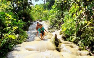 Enfants jouant et escaladant les rochers calcaires de la cascade de Buatong, entourée d'une végétation tropicale luxuriante