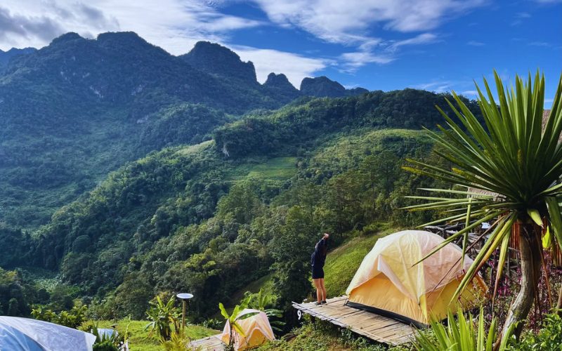 Vue panoramique sur les montagnes verdoyantes de Chiang Dao, avec des tentes installées sur des plateformes en bois pour un camping en pleine nature