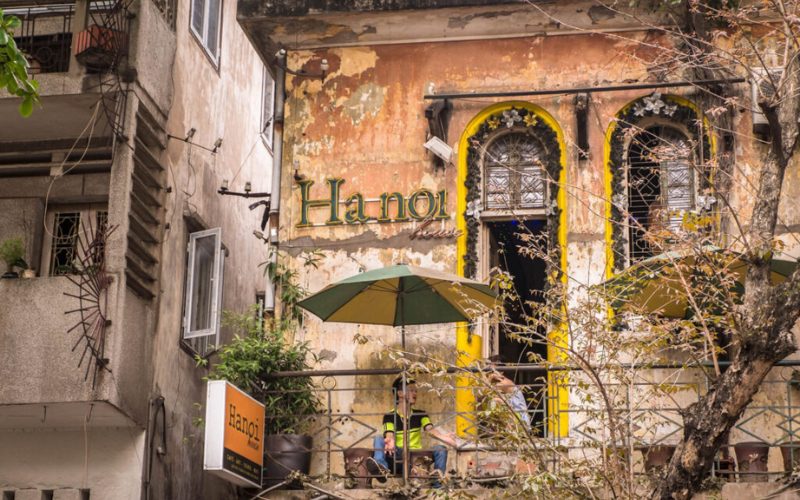 Façade d’un vieux café à Hanoï, avec murs patinés, fenêtres à vitraux et terrasse ombragée dans le quartier historique