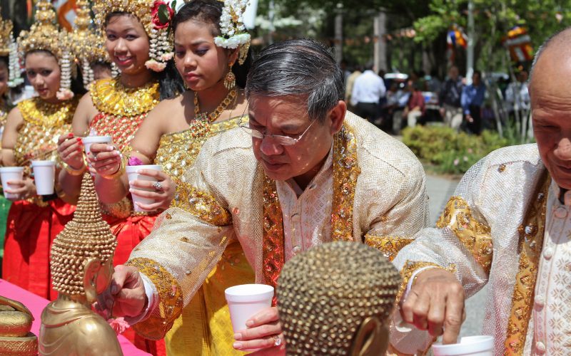 Participants vêtus de costumes traditionnels khmers versant de l’eau parfumée sur des statues de Bouddha lors de la cérémonie du Nouvel An cambodgien, Chol Chnam Thmay