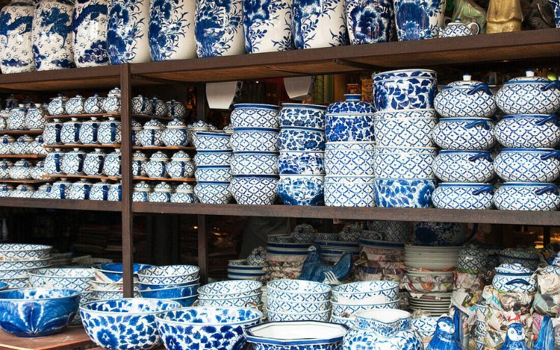 Étagères remplies de céramiques thaïlandaises traditionnelles peintes en bleu et blanc, comprenant des vases, bols, assiettes et pots décorés de motifs floraux et géométriques