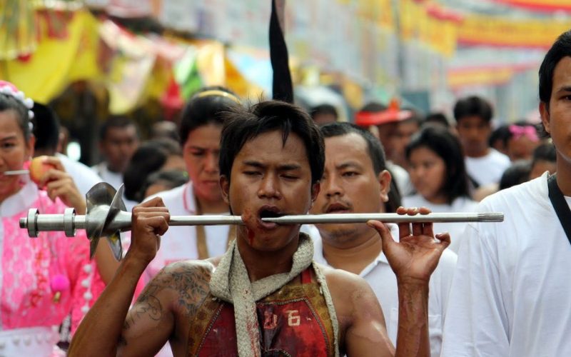 Participant en transe lors du Festival Végétarien de Phuket, se perçant la joue avec une longue tige métallique dans le cadre d’un rituel de purification et de dévotion