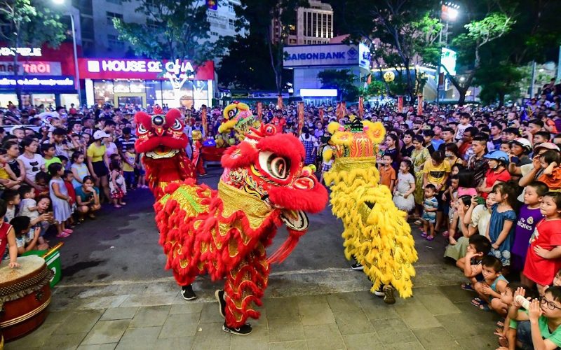 Spectacle de danse du lion animé dans une rue de Hô Chi Minh-Ville pendant le Têt Trung Thu, entouré d’une foule de familles et d’enfants émerveillés