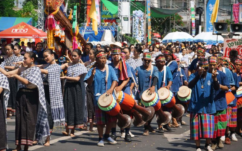 Défilé traditionnel lors du festival Bun Bang Fai en Thaïlande : des danseuses en tenues folkloriques accompagnées de musiciens jouant du tambour, dans une ambiance festive et colorée