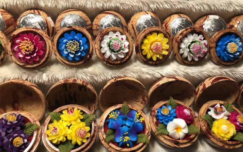 Savons artisanaux sculptés en forme de fleurs colorées, présentés dans des boîtes en bois décoratives sur un étal de marché en Thaïlande