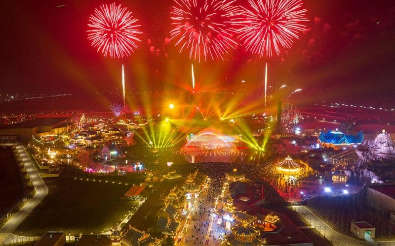 Spectacle de feux d’artifice colorés et de jeux de lumière au-dessus d’un parc d’attractions au Vietnam, célébrant le Nouvel An dans une ambiance festive et lumineuse