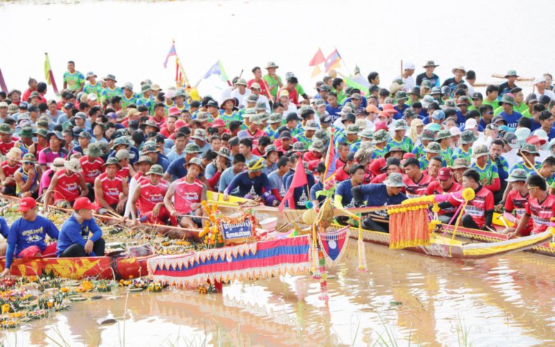 Course de pirogues traditionnelles lors d’un festival au Cambodge, avec de nombreux rameurs en uniforme coloré réunis sur la rivière