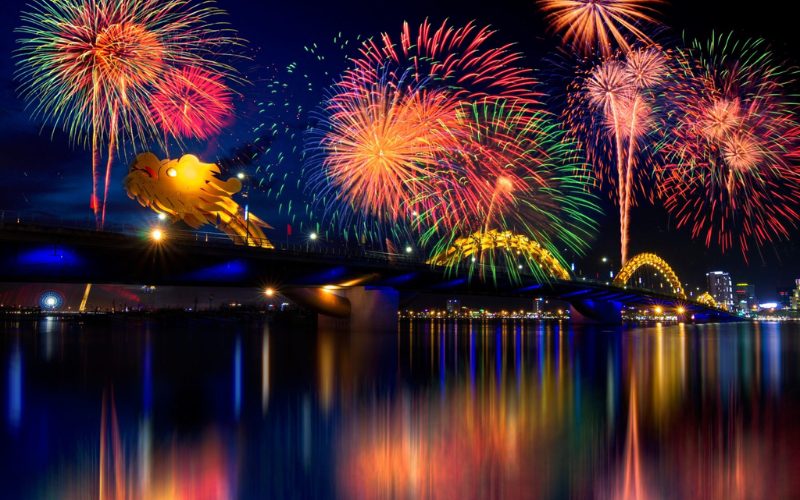 Feux d’artifice éclatants illuminant le ciel nocturne au-dessus du célèbre Pont du Dragon à Da Nang, reflétés dans les eaux calmes de la rivière Hàn