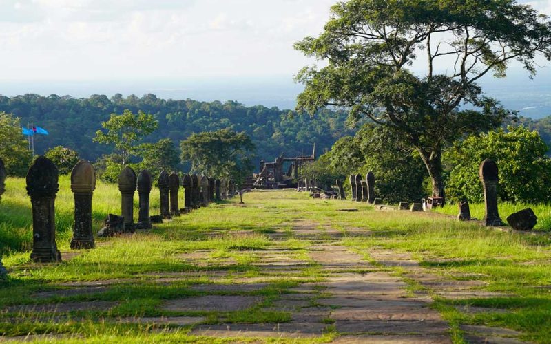Allée pavée bordée de balustrades naga menant au temple de Preah Vihear, entourée de verdure et avec vue sur les collines lointaines