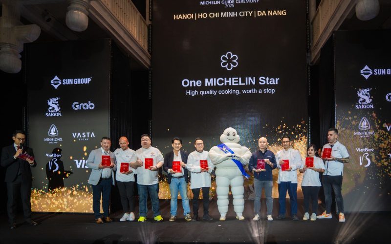 Cérémonie du Guide Michelin 2025 au Vietnam, avec les chefs récompensés d’une étoile posant sur scène aux côtés de la mascotte Michelin