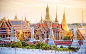 Vue spectaculaire du Grand Palais à Bangkok au coucher du soleil, mettant en valeur l'architecture dorée et colorée des temples thaïlandais