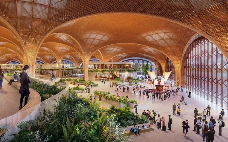 Hall principal de l’aéroport international Techo (KTI) à Phnom Penh, avec une architecture moderne en arches dorées, des espaces verts et des voyageurs