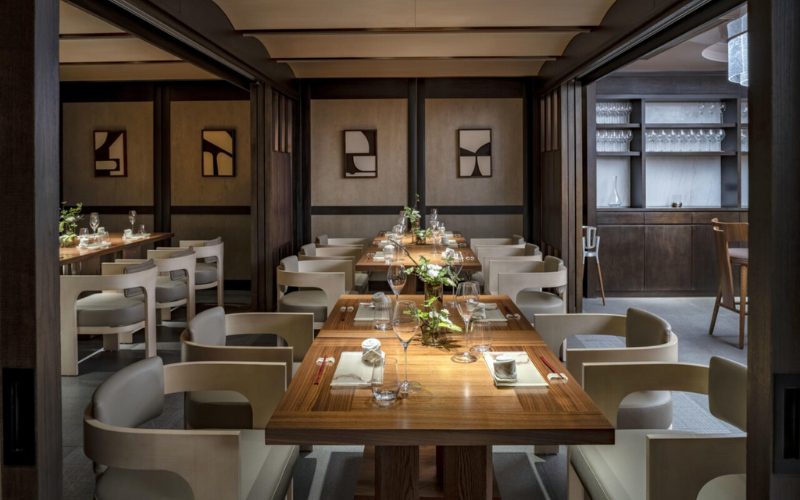 Salle à manger élégante d’un restaurant gastronomique au design moderne et épuré, avec des tables en bois soigneusement dressées, des chaises aux lignes minimalistes