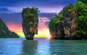 L'île James Bond à Phang Nga Bay au coucher du soleil, avec son célèbre rocher karstique émergeant des eaux et entouré de falaises verdoyantes