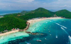 Vue aérienne de Coral Island près de Pattaya, avec ses plages de sable blanc, ses eaux turquoise, ses collines verdoyantes et de nombreux bateaux ancrés le long du littoral