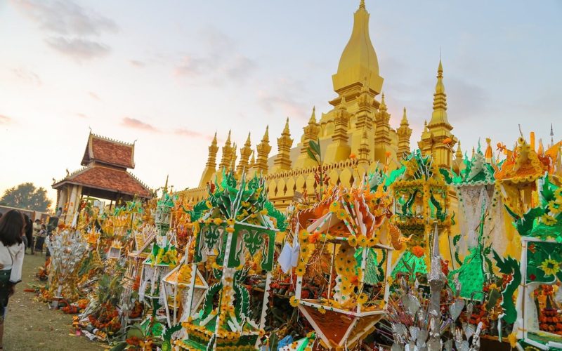 Procession de châteaux de cire colorés devant le stupa doré de Pha That Luang à Vientiane lors du Festival du That Luang au Laos