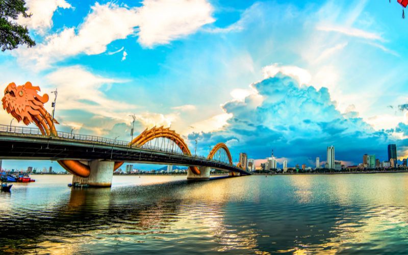 Pont du Dragon à Da Nang au coucher du soleil, avec sa structure dorée en forme de dragon s’étendant au-dessus de la rivière Han