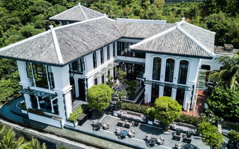 Vue aérienne d’un élégant bâtiment de style colonial indochinois, niché au cœur d’une végétation luxuriante