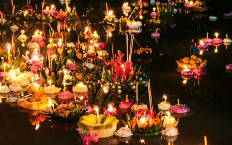 Des krathongs colorés flottant sur l’eau avec des bougies allumées lors du festival de Loy Krathong en Thaïlande