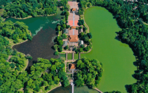 Vue aérienne du tombeau de Minh Mạng à Hué, Vietnam, entouré de lacs paisibles et d'une végétation luxuriante, illustrant l’harmonie entre l’architecture impériale et la nature.