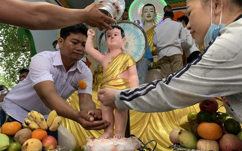 Des fidèles versent de l’eau parfumée sur une statue du Bouddha enfant lors de la cérémonie de bain rituel pendant le Nouvel An cambodgien, entourés d’offrandes de fruits