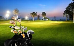 Sac de clubs de golf au premier plan sur un parcours éclairé en soirée, avec fairways bien entretenus, arbres majestueux et ciel crépusculaire coloré en arrière-plan