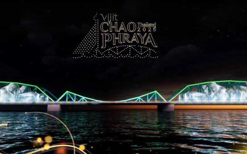 Pont Rama VIII illuminé de couleurs vives au-dessus de la rivière Chao Phraya à Bangkok, avec plusieurs bateaux lumineux naviguant sur l’eau pendant la nuit