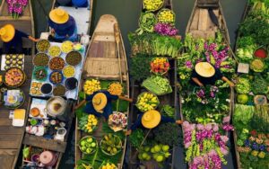 Vue aérienne d'un marché flottant coloré avec des vendeurs en bateaux proposant des fruits, légumes et fleurs