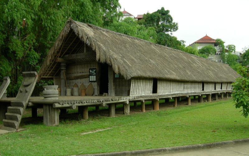 Maison traditionnelle des ethnies, construite en bois et toit de chaume, sur pilotis, dans un cadre verdoyan