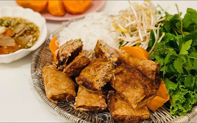 Assiette de nems vietnamiens croustillants servis avec vermicelles de riz, germes de soja, herbes fraîches et sauce nuoc-mâm parfumée. Un plat traditionnel savoureux et équilibré de la cuisine vietnamienne