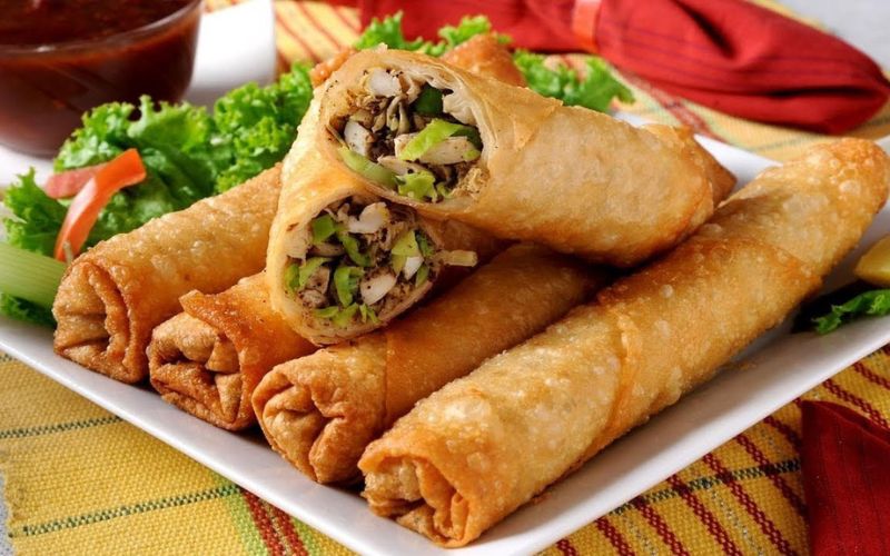 Assiette de nems vietnamiens croustillants, dorés à la perfection, garnis de légumes et de viande, servie avec de la salade verte et une sauce traditionnelle
