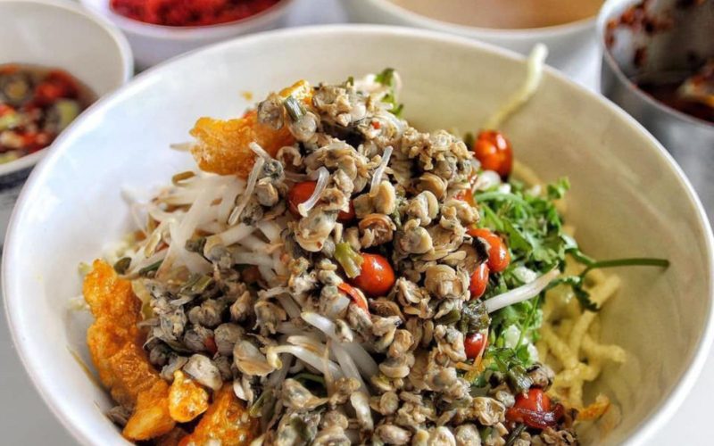 Bol de bún hến Mai Xá, nouilles vietnamiennes servies avec coques épicées sautées, légumes frais, cacahuètes et couenne croustillante