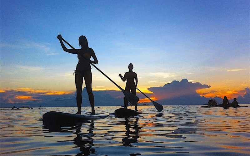 Touristes pratiquant le paddle au coucher du soleil sur la mer à Koh Samet