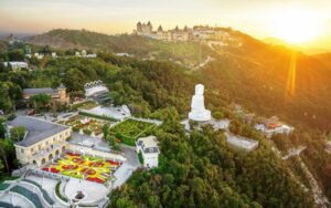 Vue panoramique des collines de Ba Na Hills près de Da Nang au coucher du soleil, avec jardins, bâtiments de style européen et grande statue de Bouddha