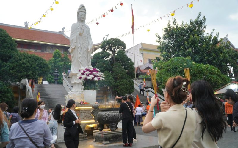 Des fidèles se recueillent et allument de l’encens devant la statue de la déesse Quan Âm dans la cour d'une pagode vietnamienne, en pleine célébration du mois du Vu Lan