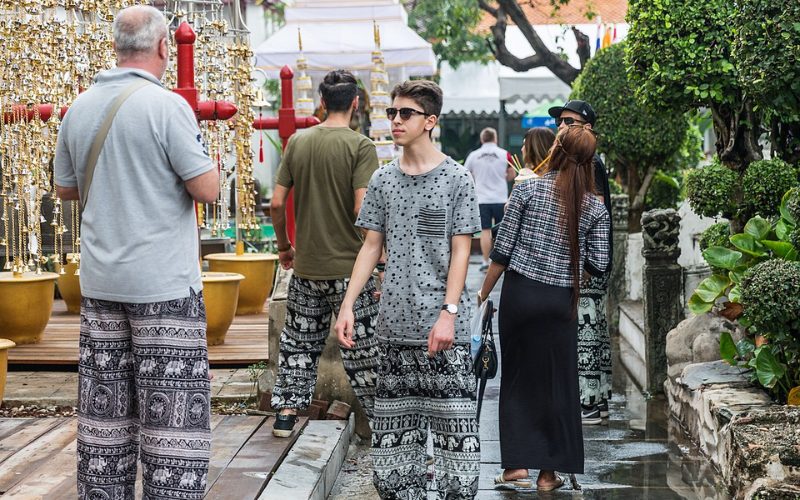 Touristes portant des pantalons thaïlandais à motifs d’éléphants et de style bohème, se promenant dans l’enceinte d’un temple en Thaïlande