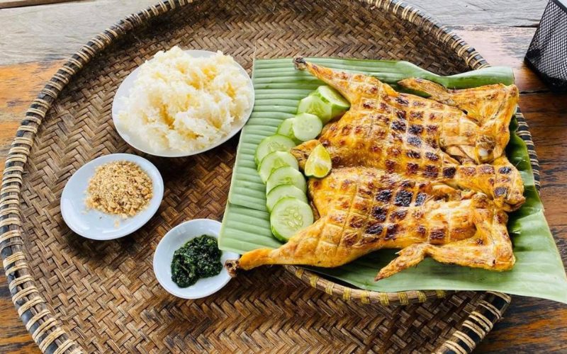 Plat traditionnel de Phong Nha composé de poulet grillé entier servi avec du riz gluant, des tranches de concombre, du sel au sésame