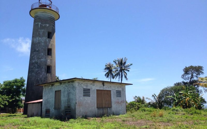 Ancien phare abandonné de Koh Rong Sanloem sous un ciel bleu, entouré de végétation tropicale et de palmiers
