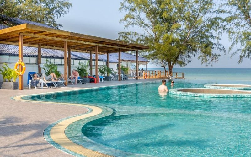 Piscine extérieure moderne au bord de la plage avec transats et espace ombragé, donnant sur la mer turquoise à Koh Rong Samloem