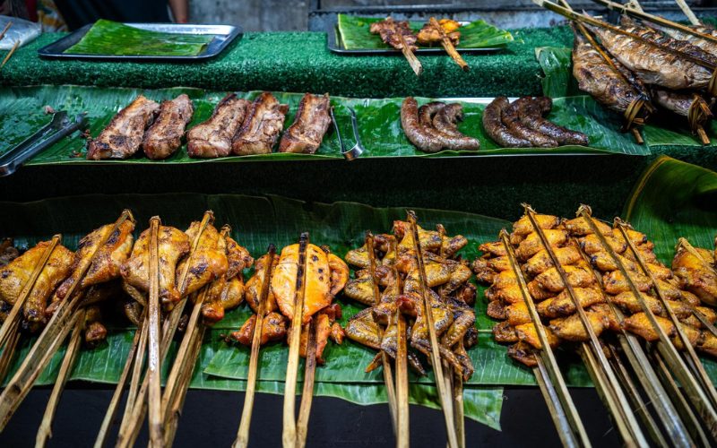 Assortiment de viandes grillées sur des brochettes, présentées sur des feuilles de bananier au marché de nuit de Luang Prabang