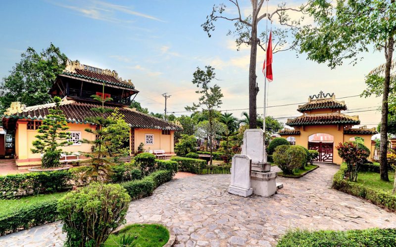 Temple de la Littérature et des Saints à Vinh Long, avec ses bâtiments traditionnels au toit en tuiles, son jardin verdoyant et son entrée ornée d’une porte ancienne