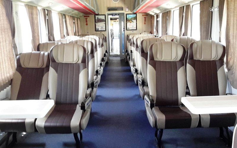 Intérieur moderne d’un wagon de train au Vietnam, avec sièges inclinables en cuir et tables pliantes, prêt à accueillir les passagers