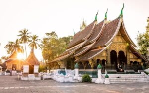 Temple Wat Xieng Thong à Luang Prabang, avec ses toits élégants descendant presque jusqu'au sol, baigné par la lumière du soleil couchant
